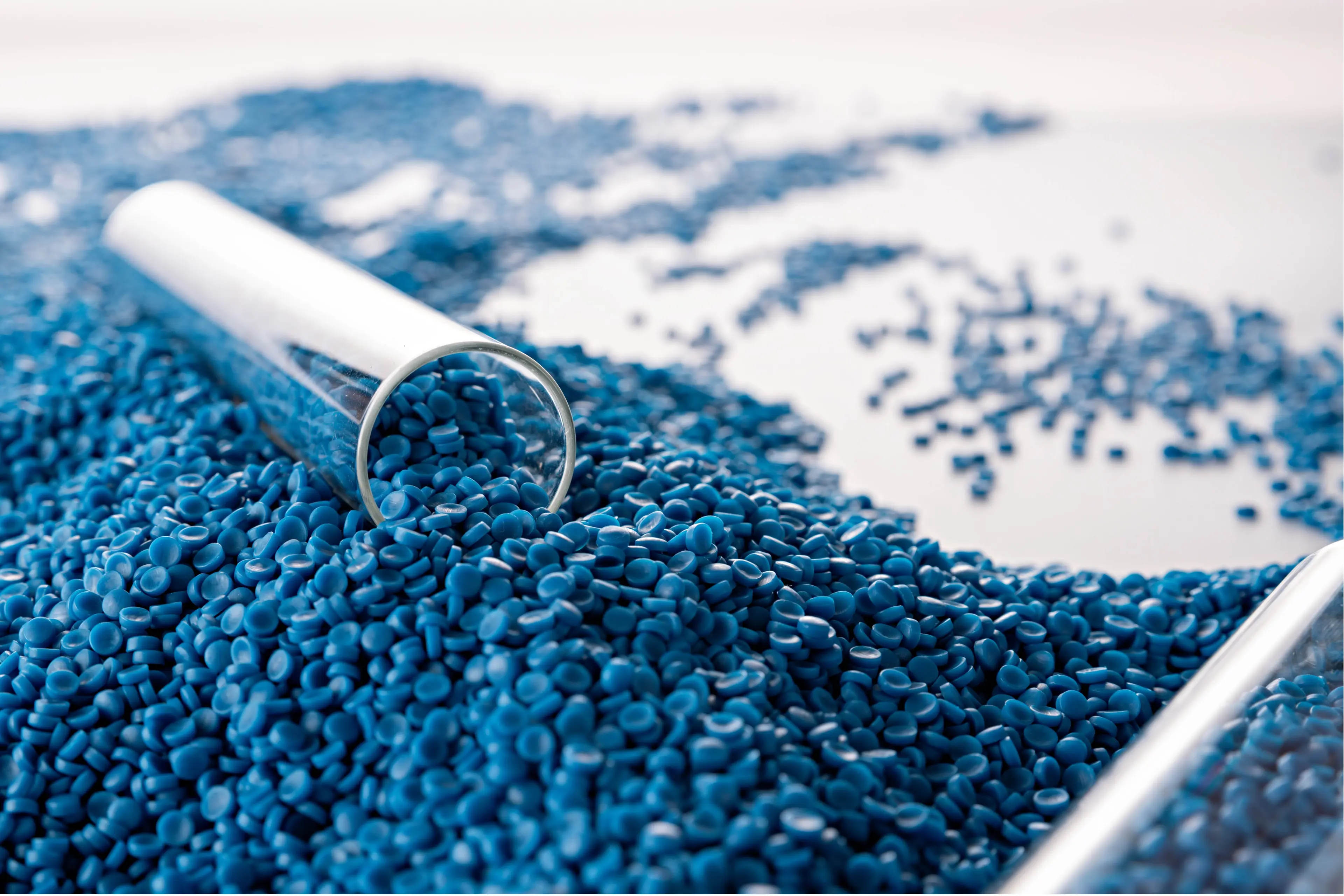 Close-up of test tube filled with blue plastic granules on a white background.